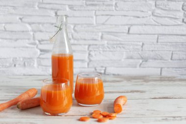 Bardakta havuç suyu ve masada taze havuç. Ahşap masa arkasında sağlıklı bir diyet içeceği..