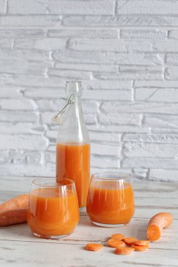 Bardakta havuç suyu ve masada taze havuç. Ahşap masa arkasında sağlıklı bir diyet içeceği..