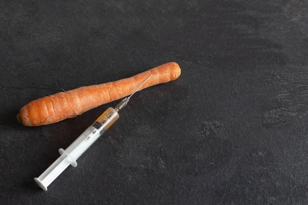 Spuit met chemicaliën en groenten op tafel, GGO-meststoffen en chemicaliën met een spuit om de houdbaarheid van groenten te verlengen. Chemische verwerking van groenten, meststoffen en gmo 's. — Stockfoto