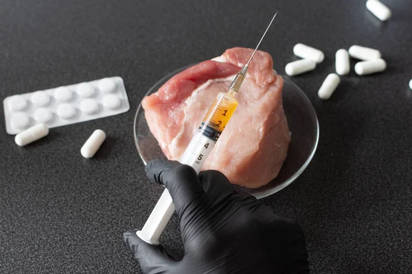 Researcher injecting GMO a slice of pork meat. Genetically modified organism, harmful for peples health. Meat with antibiotics concept.