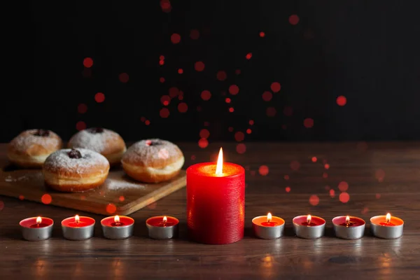 Менора со свечами (традиционная канделябра) и традиционные пончики суфганийот на деревянном столе для празднования Хануки . — стоковое фото