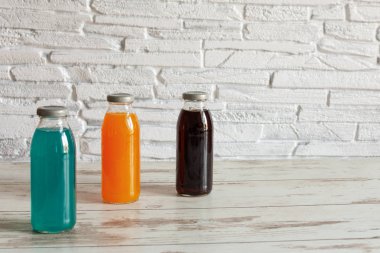 İzotonik enerji içeceği. Farklı tatlara sahip şişeler ve ahşap arka planda eklenen kombu çayı..