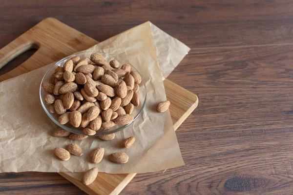 Almond nuts in a bowl on brown wooden background. — Stock Photo, Image