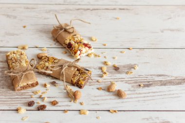 Tahta masa arkasında fındıklı, meyveli ve meyveli tahıl gevreği barı. Sağlıklı tatlı atıştırmalığı.