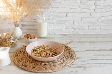Tahta bir masada badem sütüyle servis edilen kuru üzüm ve fındıklı granola. Sağlıklı kahvaltı..