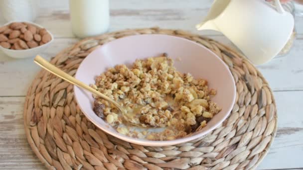 在碗里倒入杏仁牛奶和燕麦 带有葡萄干和榛子的格拉诺拉与杏仁牛奶一起放在木制桌子上 健康早餐 — 图库视频影像