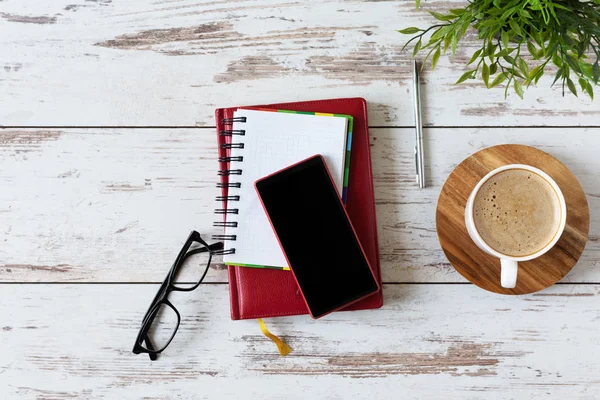 Workspace with smartphone, diary and a cup of coffee on wooden background. Stylish workplace. — Stock Photo, Image