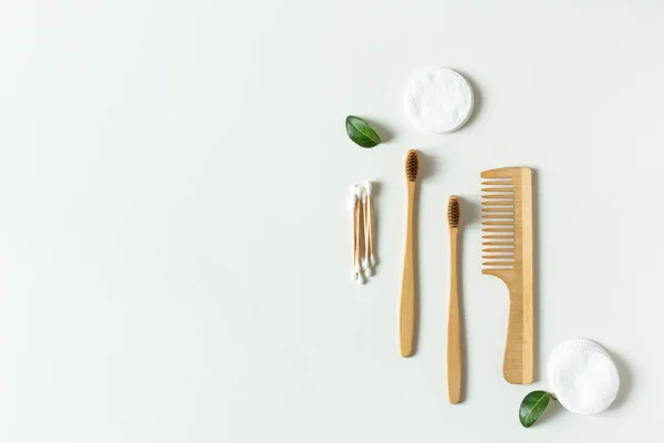 Due bio-degradabile, compostabile bambù spazzolini da denti, spazzola per capelli e batuffoli di cotone su sfondo bianco piatto lay . — Foto Stock