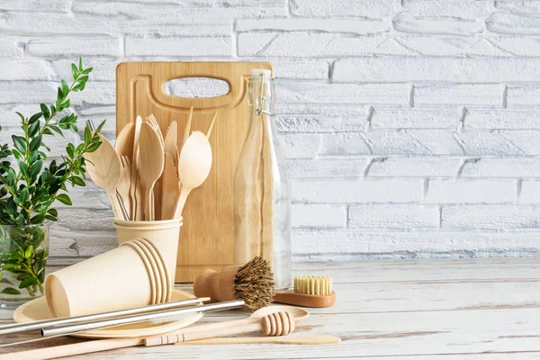 Eco-friendly utensili da cucina su sfondo di legno su muro di mattoni bianchi. . Oggetti per il servizio da tavola, spazzole, cucchiai e bottiglie . — Foto Stock