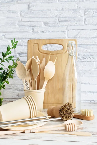 Eco-friendly utensili da cucina su sfondo di legno su muro di mattoni bianchi. . Oggetti per il servizio da tavola, spazzole, cucchiai e bottiglie . — Foto Stock