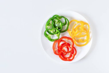 Set of colorful sliced bell pepper on plate on white background top view.