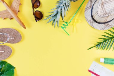 Hasır şapkalı, güneş gözlüklü, palmiye dallı, ananaslı, parmak arası terlikli ve sarı arka plan manzaralı renkli bir kompozisyon. Yaz modası, seyahat konsepti.