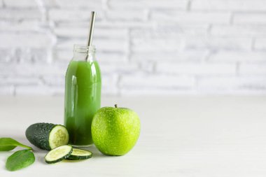Beyaz ahşap masada elma, ıspanak ve salatalıktan yapılmış bir şişe detoks yeşili smoothie. Süper yiyecek, sağlıklı yeme konsepti.