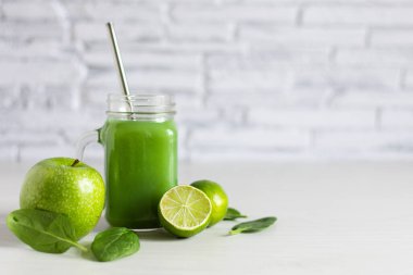 Beyaz ahşap masada elma, ıspanak ve limonla yapılmış Mason kavanozu. Süper yiyecek, sağlıklı yeme konsepti.