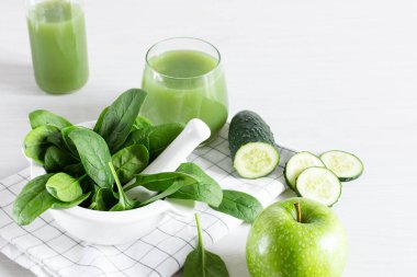 Beyaz ahşap masada elma, ıspanak ve salatalıktan yapılmış bir bardak detoks yeşili smoothie. Süper yiyecek, sağlıklı yeme konsepti.