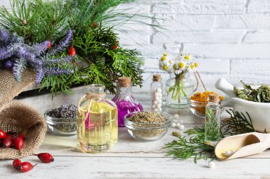 Şifalı bitkiler ve bitkisel karışım çeşitleri tuğla duvarın arkasındaki tahta masa zemininde alternatif bir ilaç konsepti olarak kullanılıyor. Homeopati tedavisi.
