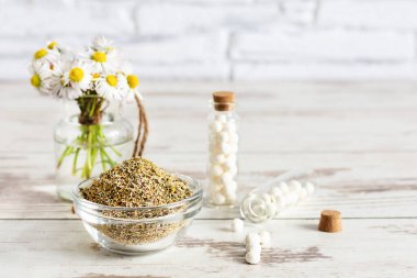 Tahta masanın üzerinde papatya çiçekleri olan homeopatik küreler. Alternatif tıp konsepti. Homeopatik ilaçlar.