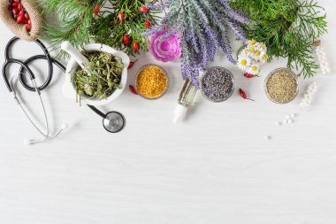 Alternatif tıp konsepti olarak ahşap masa arkası manzarasında çeşitli otlar ve bitkisel karışımlar. Homeopati tedavisi.