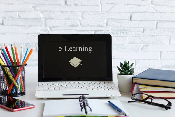 Dizüstü bilgisayarı ve kitapları olan bir iş yeri. E-öğrenme, online eğitim konsepti. İnternet üzerinden uzaklık öğrenme.