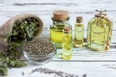 Kenevir tohumlu kenevir yağı şişeleri ve beyaz ahşap masa üzerinde kuru yapraklar. Tıbbi CBD yağı. Alternatif tıp konsepti.