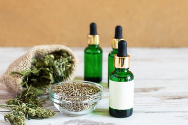Kenevir tohumlu kenevir yağı şişeleri ve beyaz ahşap masa üzerinde kuru yapraklar. Tıbbi CBD yağı. Alternatif tıp konsepti.