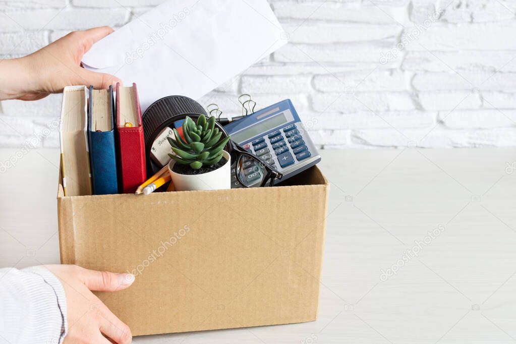 Business woman packing personal company belongings into cardboard box. Dismissal or resignation concept. Company bankruptcy and economy crisis.