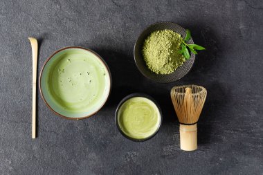 Organik yeşil kibrit çayı. Bir kasede kibrit tozu ve kibrit çayı. Chashaku kaşığı ve chasen bambu çırpısı siyah arkaplanda çay demlemek için..