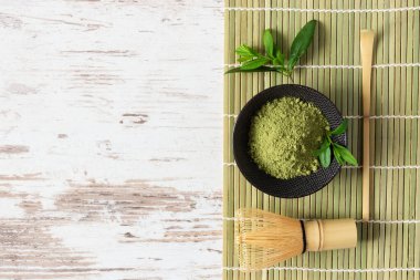 Beyaz ahşap arka plan manzaralı yeşil kibrit çay tozu ve çay aksesuarları. Japon çay tarifi konsepti. Chashaku kaşığı ve çay demlemek için bambu çırpıcı..