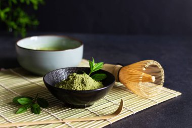 Siyah arka planda organik yeşil kibrit çay ve çay aksesuarları. Japon çay töreni konsepti. Chashaku kaşığı ve çay demlemek için bambu çırpıcı..