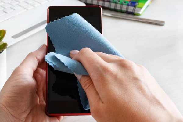 Woman hand disinfecting smartphone screen with antibacterial cloth. Hygiene concept and protection against bacteria.