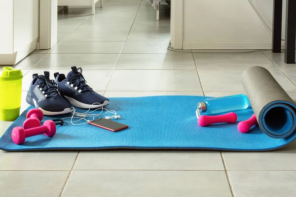 Fitness sports equipment and smartphone on the floor in living room. Home online workout concept. Fitness online training.
