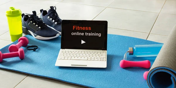 Spor malzemeleri ve gri çimento arka planda dizüstü bilgisayar. Evde online egzersiz konsepti. Fitness çevrimiçi eğitim.