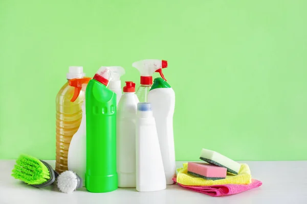 Bottles of detergent and cleaning tools over green background. Housework cleaning concept.