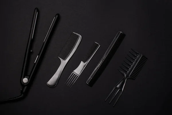 combs and hairdresser tools on black background top view