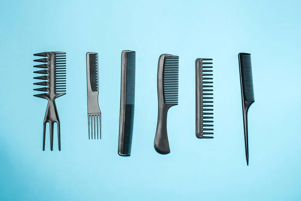 combs and hairdresser tools on blue background top view