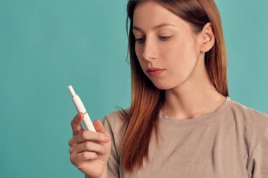 Elektronik Sigara Teknolojisi. Tütün Iqos sistemi. Isıtma yastığıyla elektrikli sigara içen bir kızın yakın çekimi. tütün ısıtma sistemi.