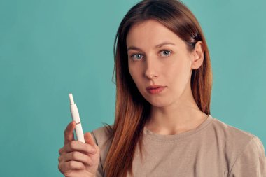 Elektronik Sigara Teknolojisi. Tütün Iqos sistemi. Isıtma yastığıyla elektrikli sigara içen bir kızın yakın çekimi. tütün ısıtma sistemi.