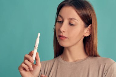 Elektronik Sigara Teknolojisi. Tütün Iqos sistemi. Isıtma yastığıyla elektrikli sigara içen bir kızın yakın çekimi. tütün ısıtma sistemi.