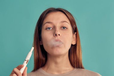 Elektronik Sigara Teknolojisi. Tütün Iqos sistemi. Isıtma yastığıyla elektrikli sigara içen bir kızın yakın çekimi. tütün ısıtma sistemi.