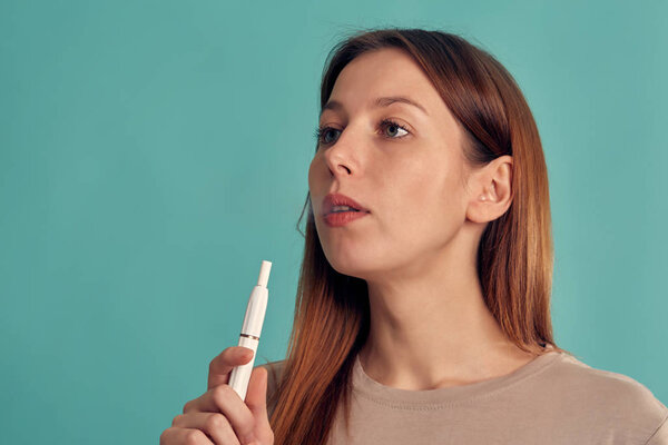 Electronic Cigarette Technology. Tobacco IQOS system. Close-up of a girl smoking an electric hybrid cigarette with a heating pad. tobacco heating system.