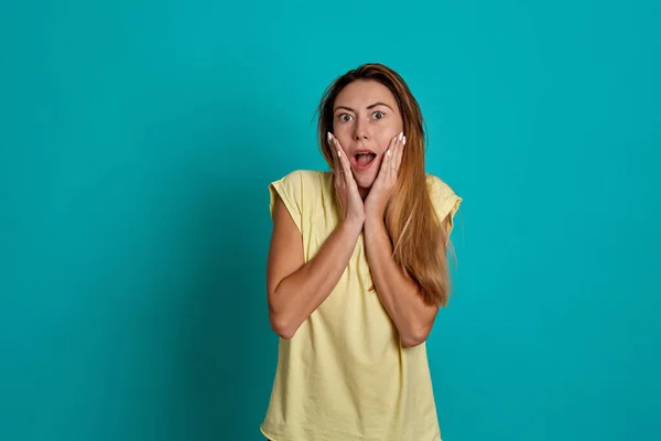 Retrato de estudio de una joven guapa de pelo rubio. Emociones de una chica sobre un fondo azul . — Foto de Stock