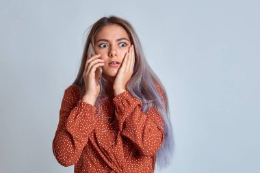 Genç bir kız telefonda şok edici haberler öğreniyor. Kız telefona duygusal olarak bakıyor..