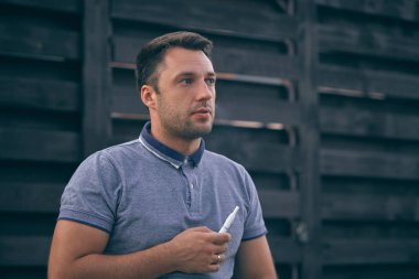 Elektronik sigara, sigara teknolojisi. Tütün Iqos sistemi. Isıtıcıyla elektrikli sigara içen bir adamın yakın çekimi. Yeni tütün ısıtıcısı yanıyor.