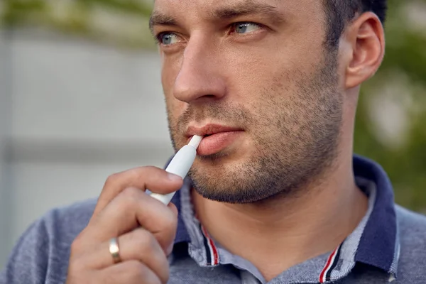 Elektronik sigara, sigara teknolojisi. Tütün Iqos sistemi. Isıtıcıyla elektrikli sigara içen bir adamın yakın çekimi. Yeni tütün ısıtma sistemi yakılmadan.