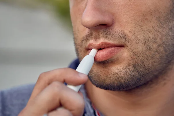 Elektronik sigara, sigara teknolojisi. Tütün Iqos sistemi. Isıtıcıyla elektrikli sigara içen bir adamın yakın çekimi. Yeni tütün ısıtma sistemi yakılmadan.