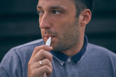 Elektronik sigara, sigara teknolojisi. Tütün Iqos sistemi. Isıtıcıyla elektrikli sigara içen bir adamın yakın çekimi. Yeni tütün ısıtıcısı yanıyor.