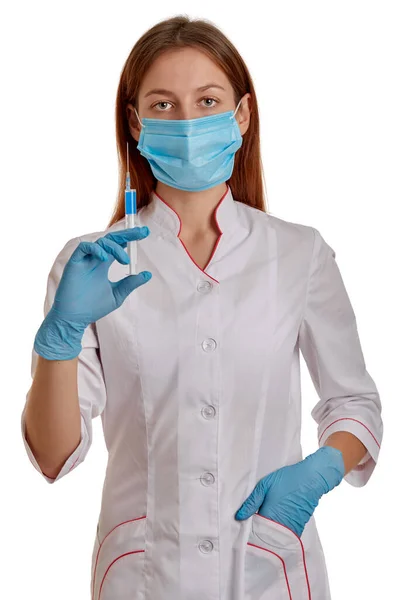 Le médecin, vêtu d'un manteau blanc sur fond blanc, tient une seringue avec des médicaments dans les mains. Une infirmière dans un masque respiratoire se protège du nouveau coronavirus qui se propage rapidement. Le concept de m — Photo