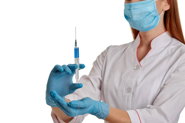 O médico com um casaco branco em um fundo branco segura uma seringa com o medicamento em suas mãos. Uma enfermeira com uma máscara respiratória protege-se do novo coronavírus que se espalha rapidamente. O conceito de m — Fotografia de Stock