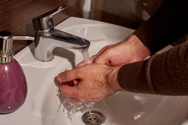 Musluğun altında sabunla ellerini yıka. Coronavirüs 'ün yayılmasını önlemek için sabun ve su ile el yıkama ve hijyen..