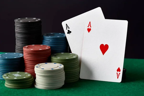 Poker chips and cards on a green poker canvas. Gambling, poker, casino concept. Black background. Close-up. Success in playing cards.